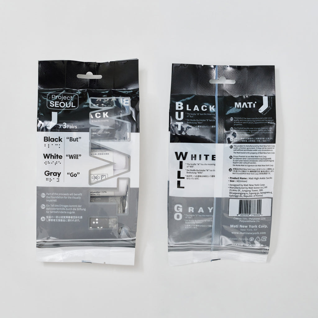 Product photography of Project Seoul and Mati New York Corp high ankle socks on a white background, featuring two black and white packages displaying braille alongside Black But White Will Gray Go, text about supporting the visually impaired, and visible black, white, and gray socks from Korea